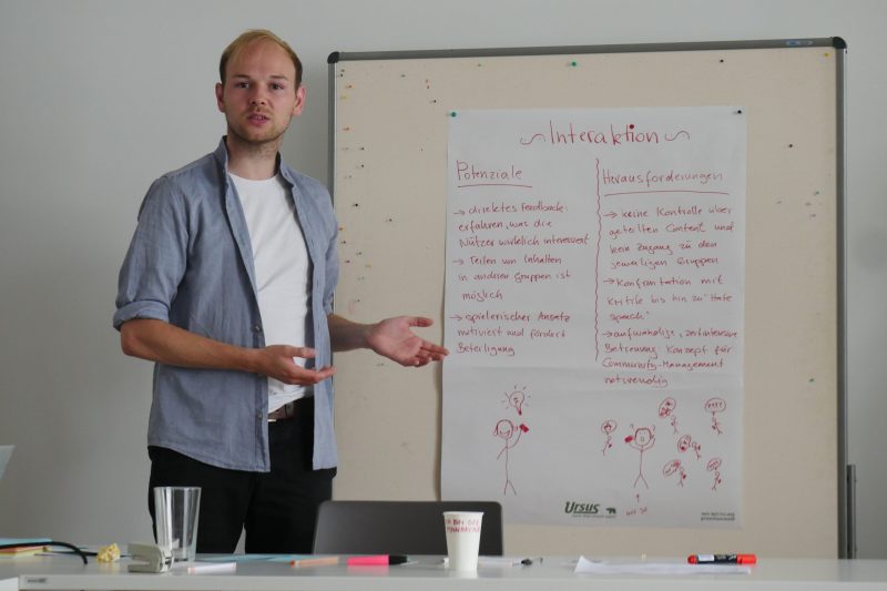 Eine männliche Person steht vor einem Poster zum Thema Herausforderungen und Potenziale von Interaktion in Bezug auf Messengerdienste